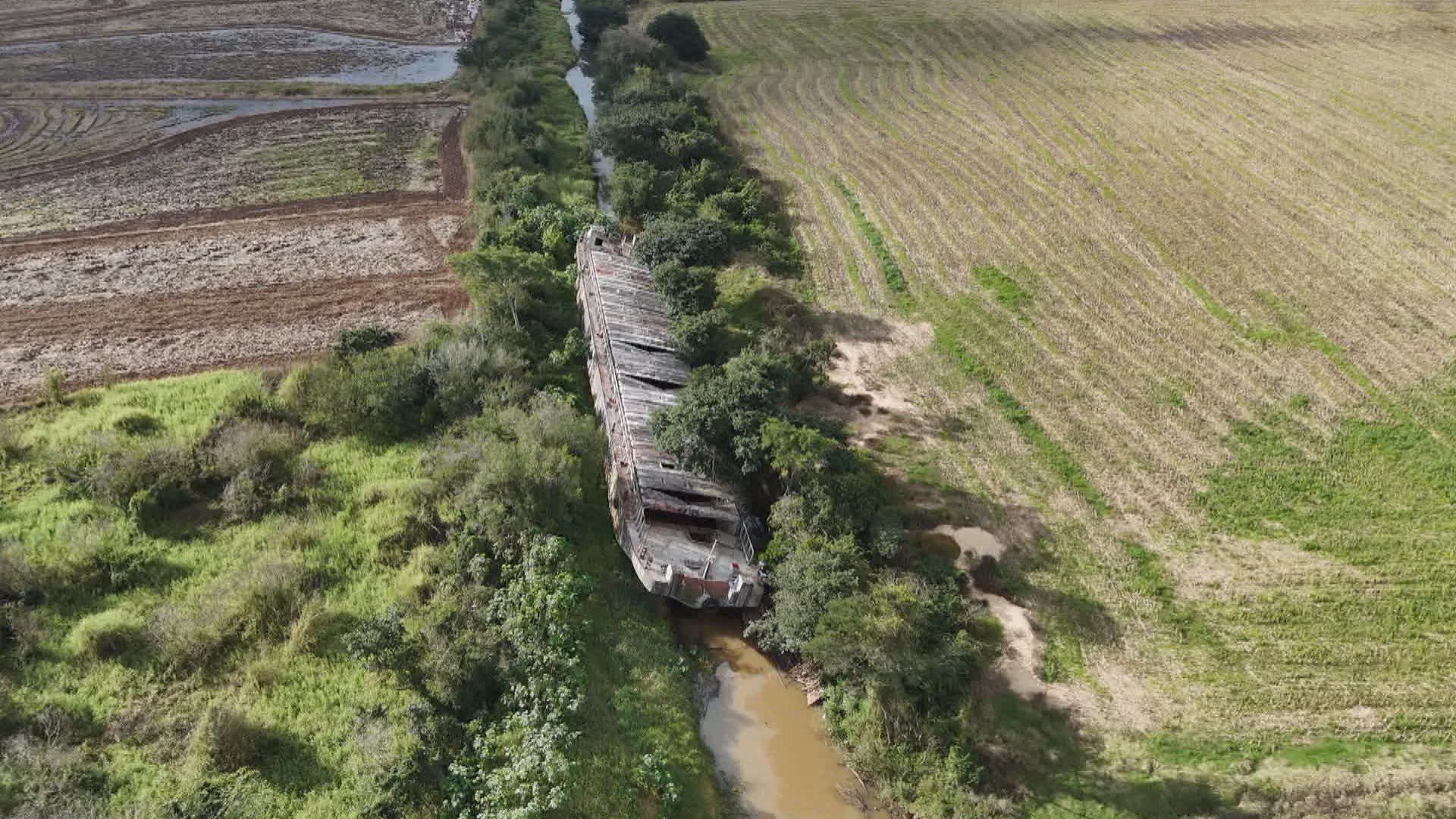 Embarcação encalhada em enchente há mais de um ano ainda bloqueia canal de irrigação no RS; chuvas podem ajudar na remoção